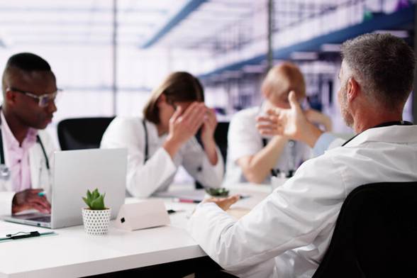 Male talking to female employee with head in her hands - Hostile Work Environment